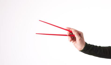 a hand holding a set of chopsticks