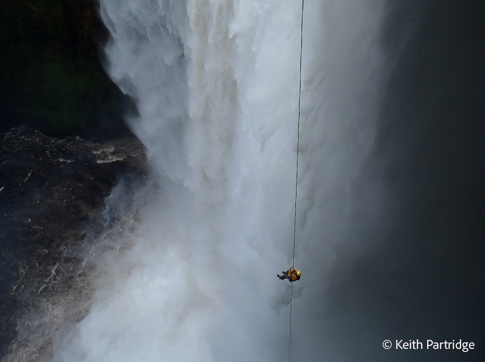 Ollie Laker hangs on a long rope midway down a tall waterfall