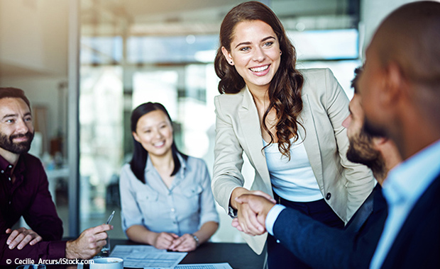 Two people shake hands in a meeting