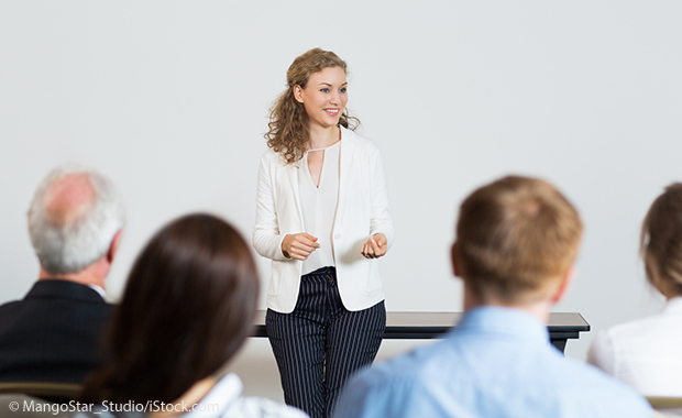 Tipps für englische Präsentationen - lächelnde Frau hält einen Vortrag vor einer kleinen Menschengruppe