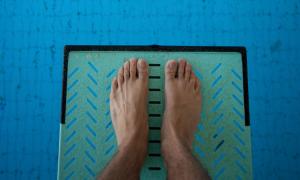 man looking down on his feet on diving board