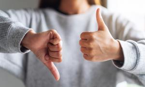 Close-up image of a woman with one thumb up and one thumb down