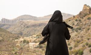 Woman wearing abaya looking out over a rugged landscape