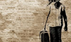 : Graffiti/shadow on a brickwall showing a refugee girl walking with her suitcase