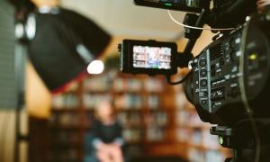 woman being interviewed in front of cameras in a library