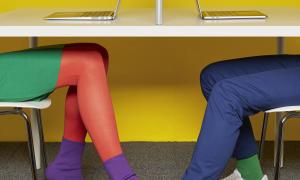 two people playing footie under table while working
