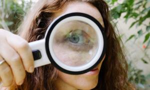 the giant eye of a girl looking at you from behind a magnifying glass