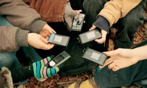 Luddite Club members hold out their matching flip phones in Prospect Park in Brooklyn, Dec. 11, 2022.