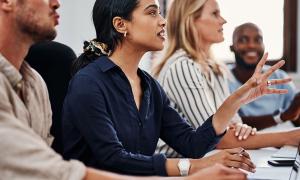 A woman speaks in a meeting with colleagues