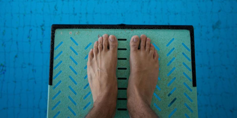 man looking down on his feet on diving board