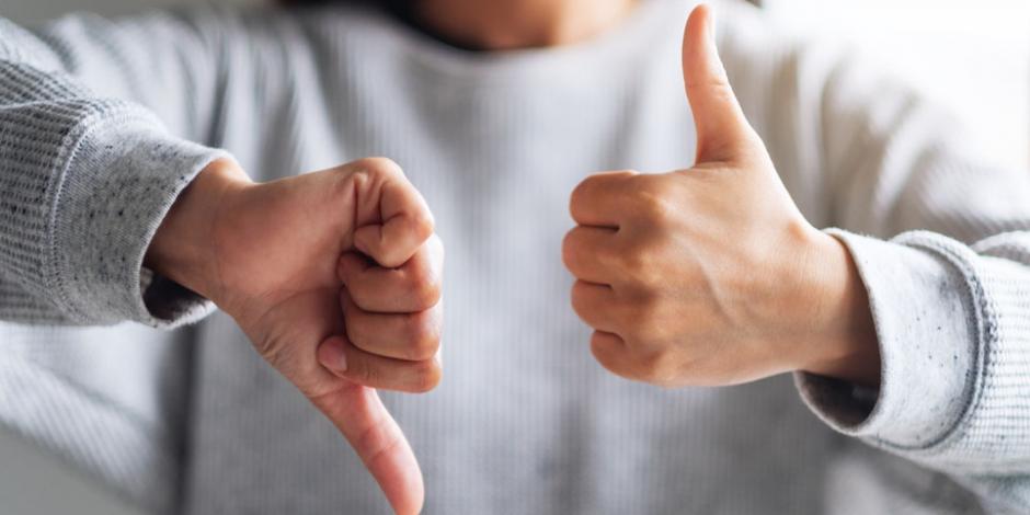 Close-up image of a woman with one thumb up and one thumb down