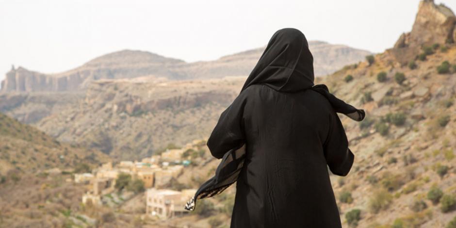 Woman wearing abaya looking out over a rugged landscape