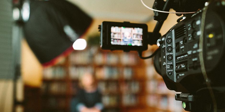 woman being interviewed in front of cameras in a library