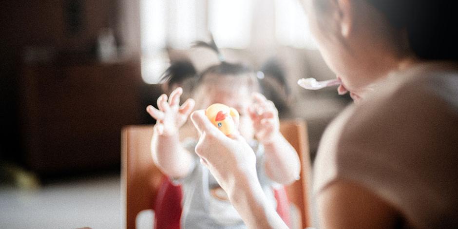 mom feeding child and holding rubber duck