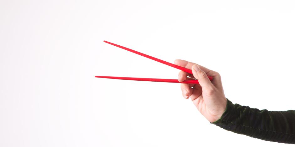 a hand holding a set of chopsticks