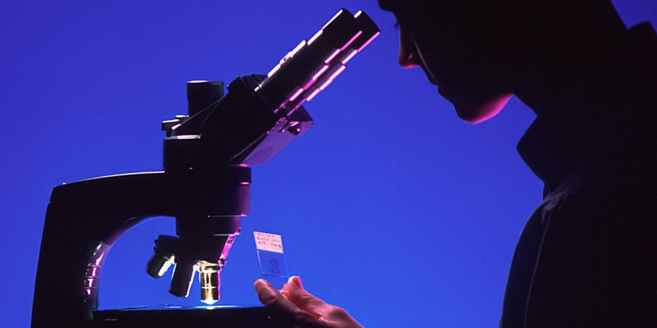 Woman at a microscope in a dark room