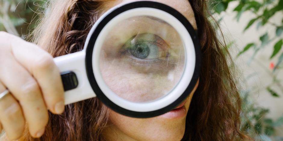 the giant eye of a girl looking at you from behind a magnifying glass