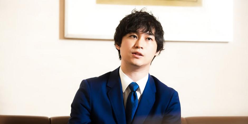 Shunsaku Sagami speaks while sitting on a couch