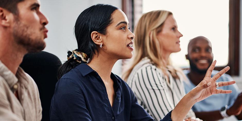 A woman speaks in a meeting with colleagues