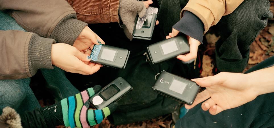 Luddite Club members hold out their matching flip phones in Prospect Park in Brooklyn, Dec. 11, 2022.