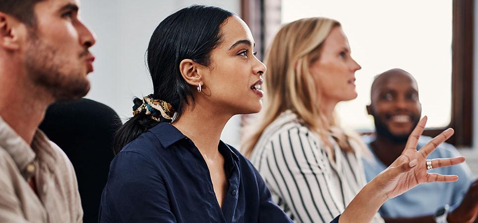A woman speaks in a meeting with colleagues
