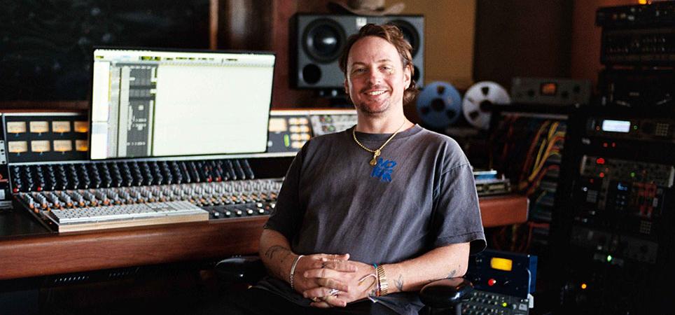 Kid Harpoon sitting at a mixing console inside a recording studio