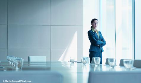 Frau im Business-Look steht in einem leeren Büro.