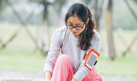 Frau mit Fitnesstracker schnürt sich die Schuhe zu