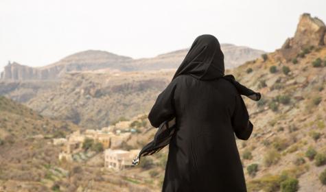 Woman wearing abaya looking out over a rugged landscape