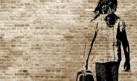 : Graffiti/shadow on a brickwall showing a refugee girl walking with her suitcase