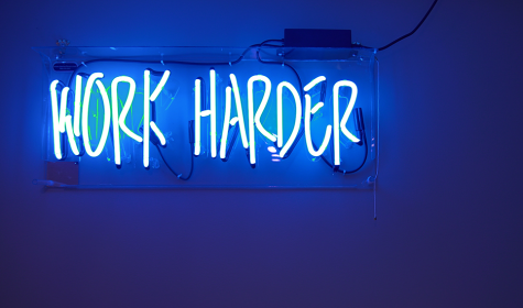 blue neon sign saying "work harder"