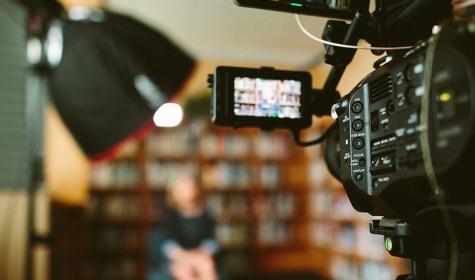 woman being interviewed in front of cameras in a library