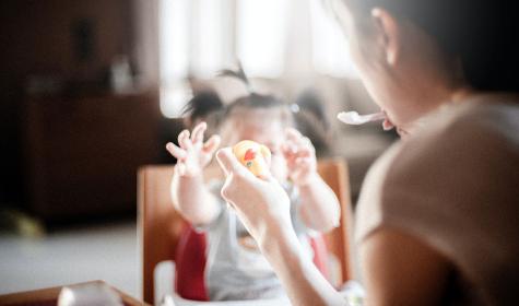 mom feeding child and holding rubber duck