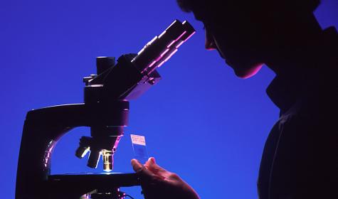 Woman at a microscope in a dark room