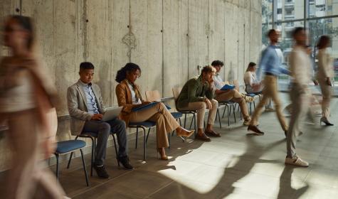 a row of professionally dressed applicants seated and standing near a concrete wall