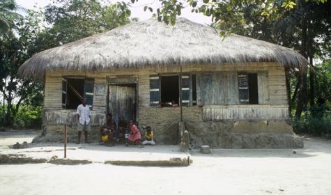 a simple house with a family sitting close together in front of it