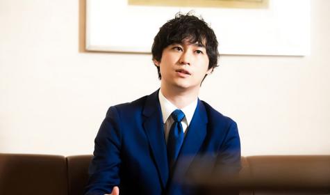 Shunsaku Sagami speaks while sitting on a couch