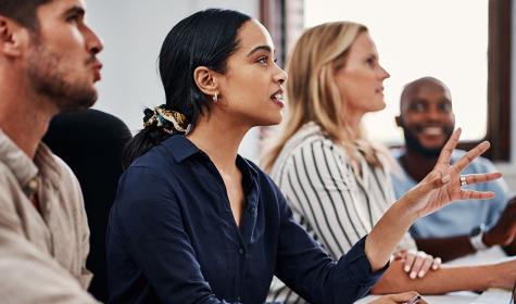 A woman speaks in a meeting with colleagues
