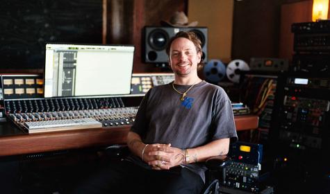Kid Harpoon sitting at a mixing console inside a recording studio